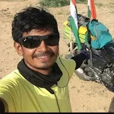 NL01 Kundan smiling in sunglasses beside a loaded motorbike on a desert road